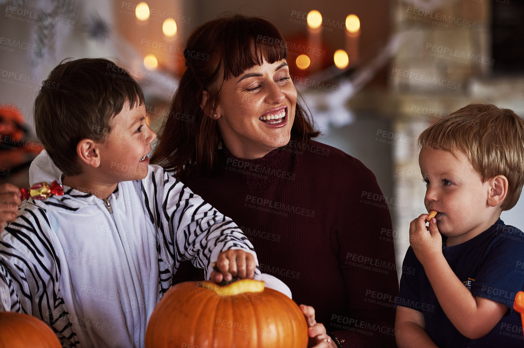 Buy stock photo Shot of two adorable little boys carving out pumpkins and celebrating halloween with their mother at home