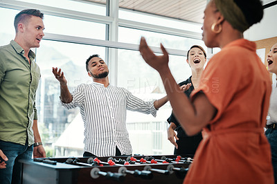 Buy stock photo Cropped shot of a diverse group of businesspeople standing together and bonding over a game of foosball in the office