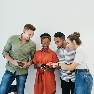 Buy stock photo Cropped shot of a diverse group of businesspeople standing against a gray background together and using technology in the office