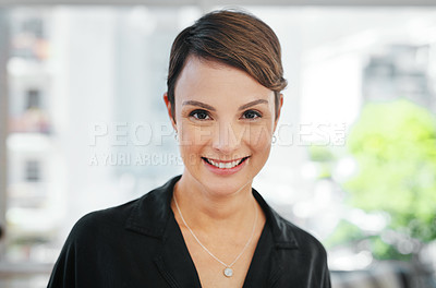Buy stock photo Cropped portrait of an attractive young businesswoman standing alone in the office and smiling at the camera