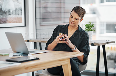 Buy stock photo Cropped shot of an attractive young businesswoman sitting alone and texting on her cellphone in the office