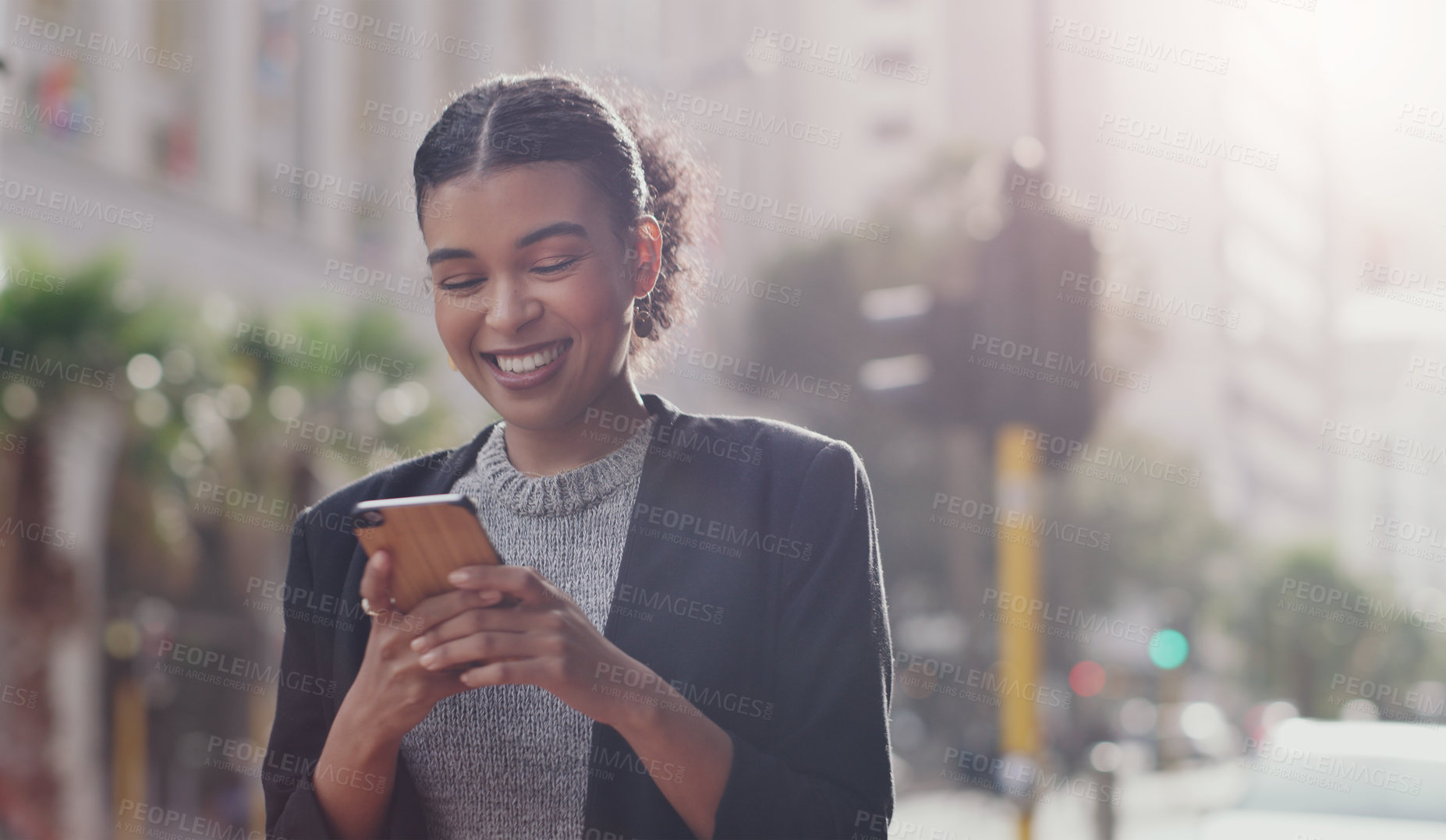 Buy stock photo Cropped shot of an attractive young businesswoman smiling while using a smartphone outdoors in the city