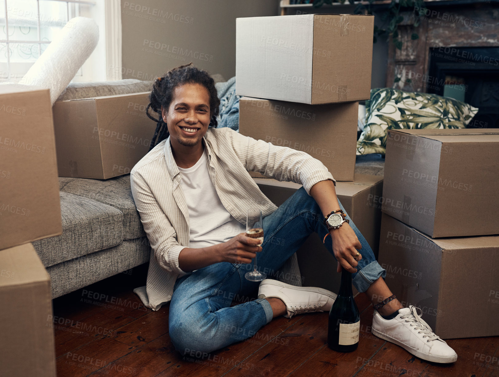Buy stock photo Shot of a handsome young man having champagne to celebrate moving into his new house