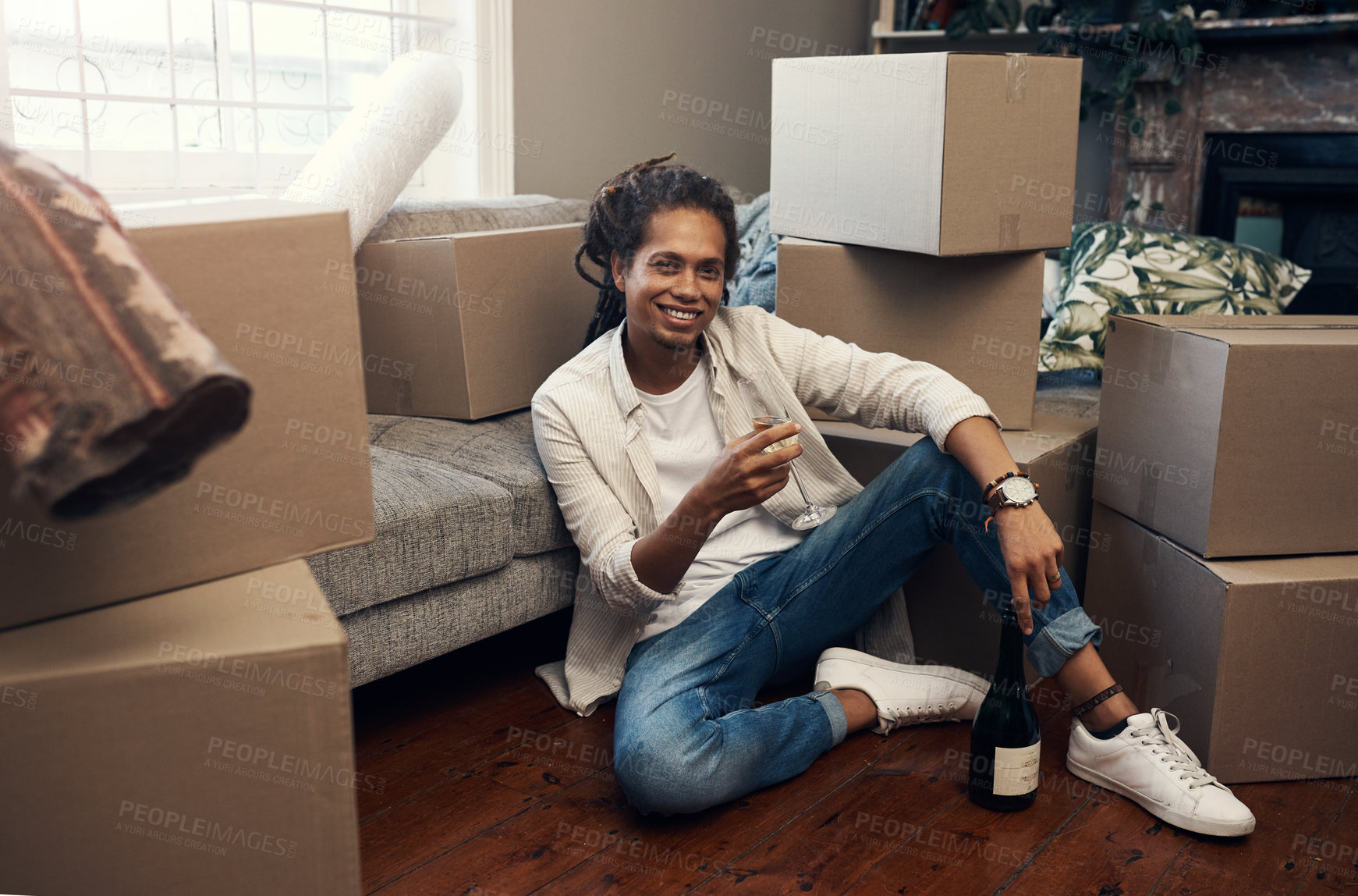 Buy stock photo Shot of a handsome young man having champagne to celebrate moving into his new house