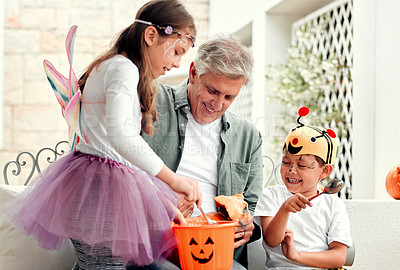 Buy stock photo Shot of two adorable young siblings carving out pumpkins for Halloween with their grandfather at home