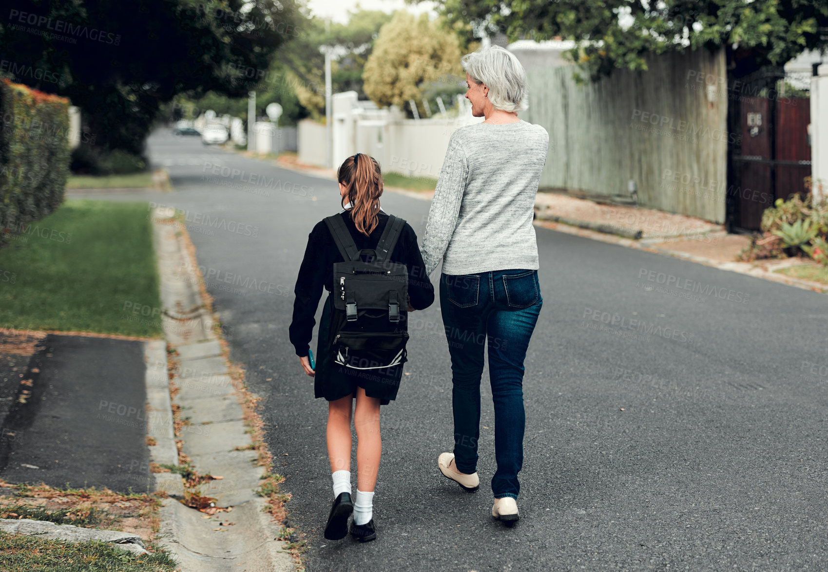 Buy stock photo Full length shot of a young school girl walking with her grandmother to school in the streets in their neighborhood