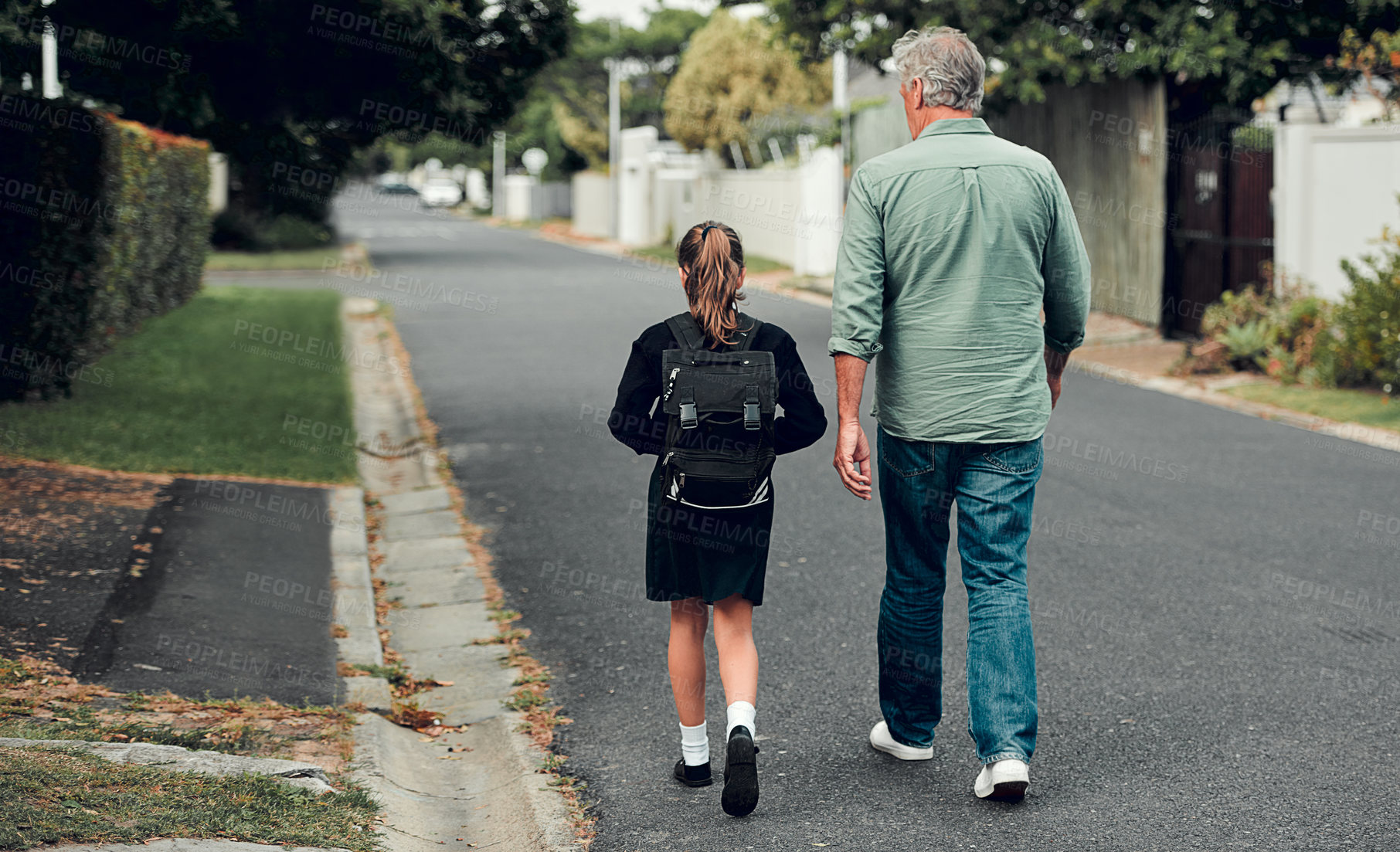 Buy stock photo Full length shot of a young school girl walking with her grandfather to school in the streets in their neighborhood