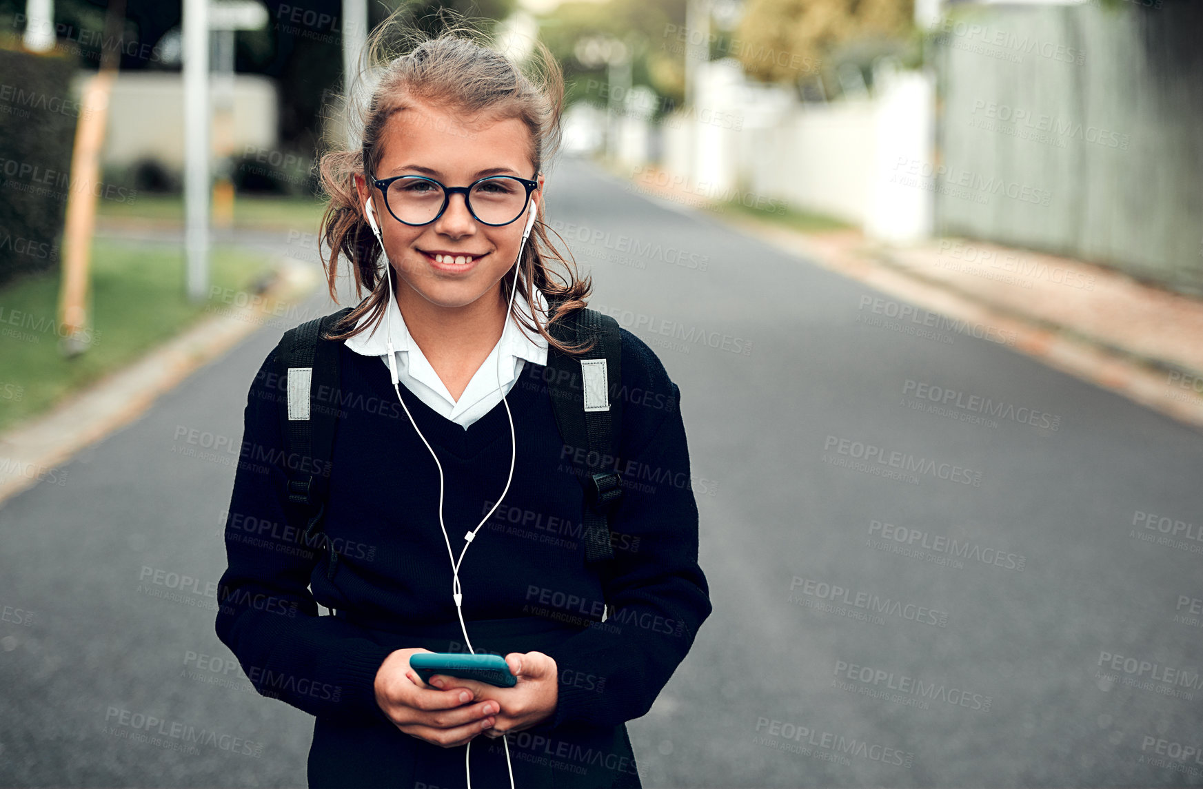 Buy stock photo Portrait of an adorable young schoolgirl listening to music and using her cellphone while walking to school
