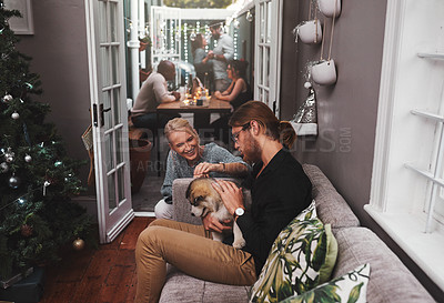 Buy stock photo Cropped shot of two cheerful friends hanging out together with a puppy in the living room at home during christmas time