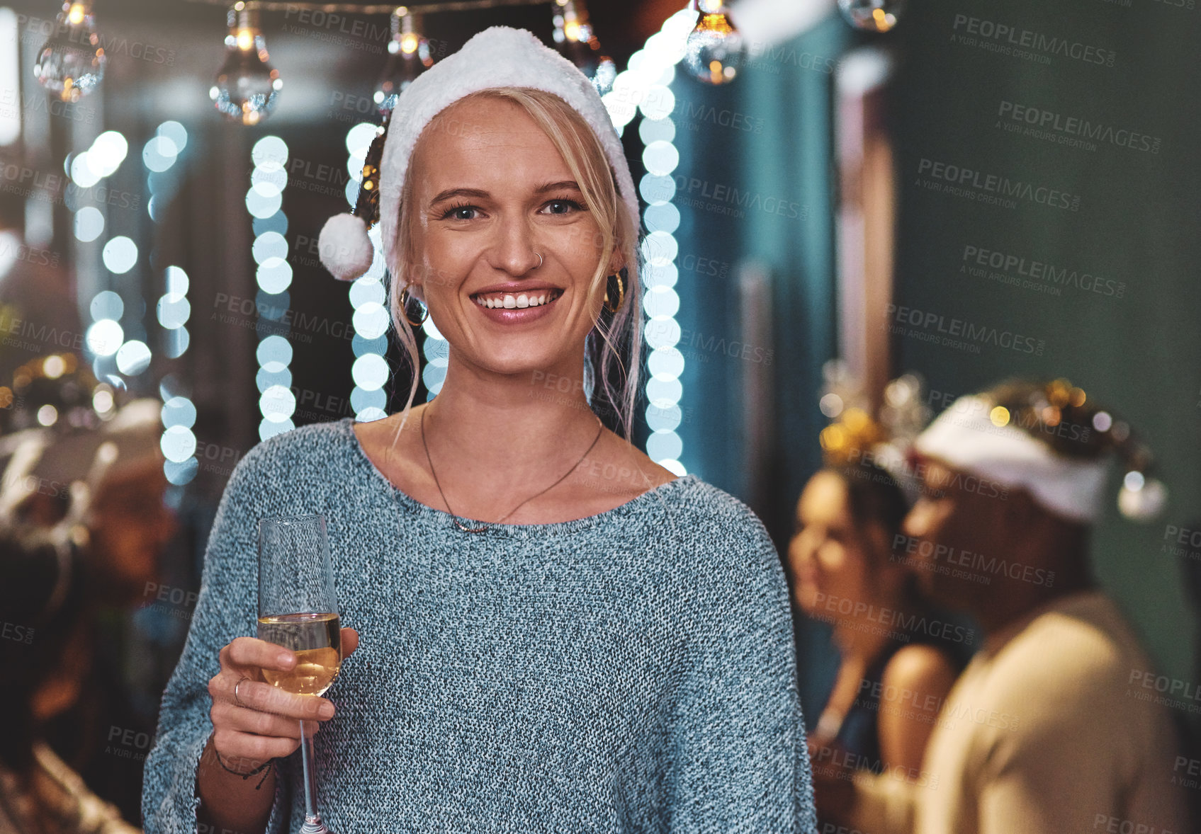Buy stock photo Portrait of a cheerful young woman wearing a festive hat and holding a glass of wine at home during christmas time
