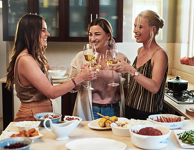 Buy stock photo Cropped shot of a group of cheerful young friends having a celebratory toast with drinks while standing in the kitchen preparing food at home