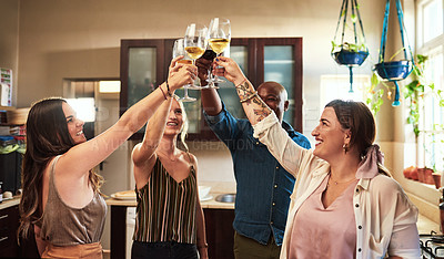 Buy stock photo Cropped shot of a group of cheerful young friends having a celebratory toast with drinks while standing in the kitchen preparing food at home