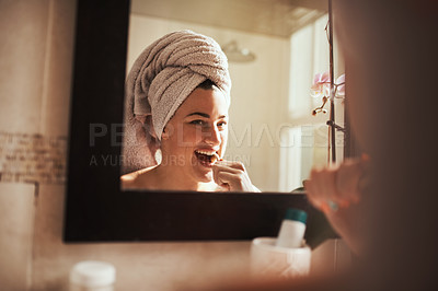Buy stock photo Shot of an attractive young woman brushing her teeth in the bathroom at home