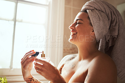 Buy stock photo Shot of a young woman spraying perfume during her morning beauty routine