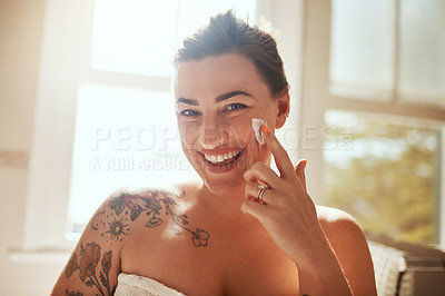 Buy stock photo Shot of an attractive young woman applying moisturiser during her morning beauty routine