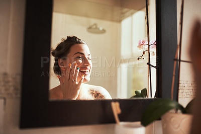Buy stock photo Shot of an attractive young woman applying moisturiser during her morning beauty routine
