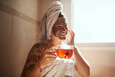 Buy stock photo Shot of a young woman having tea while giving herself a facial at home