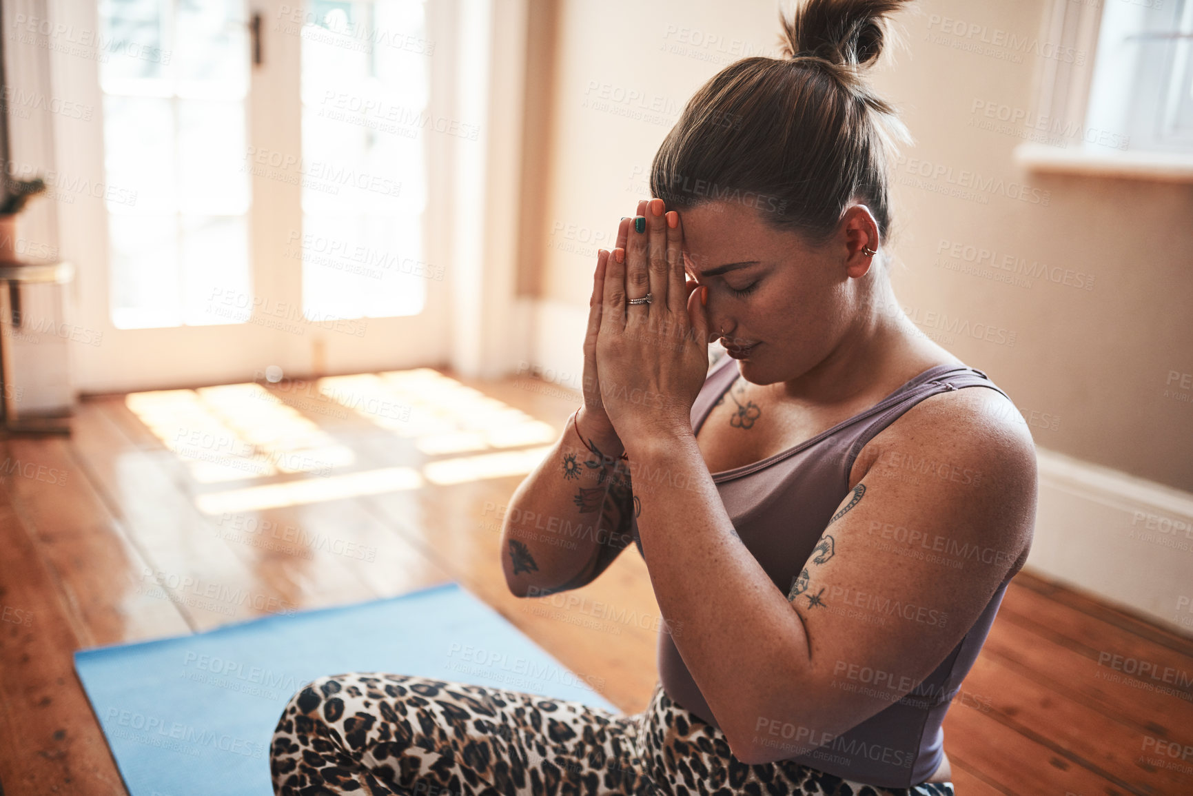 Buy stock photo Shot of a young woman meditating on a yoga mat at home