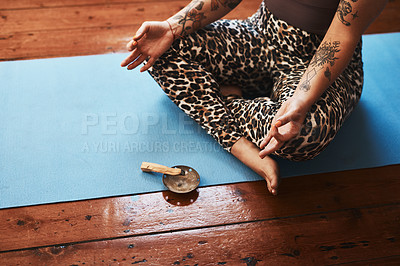 Buy stock photo Closeup shot of a woman burning a palo santo stick while meditating on a yoga mat at home