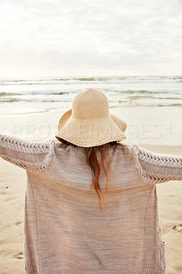 Buy stock photo Rearview shot of a young woman standing with her arms outstretched at the beach