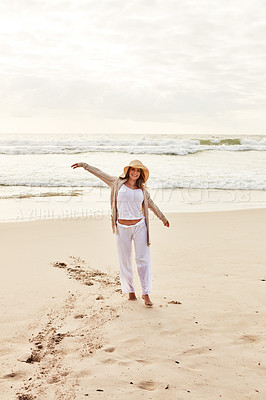 Buy stock photo Shot of a young woman standing with her arms outstretched at the beach