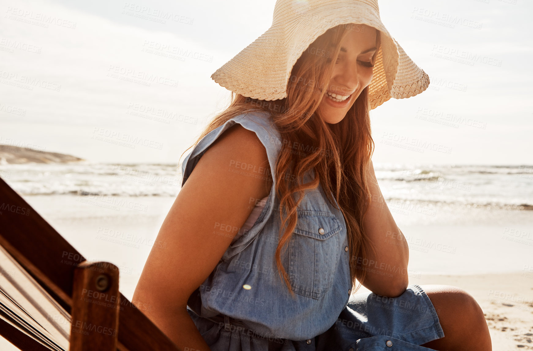 Buy stock photo Shot of a young woman relaxing on a lounger at the beach