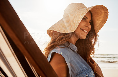 Buy stock photo Shot of a young woman relaxing on a lounger at the beach