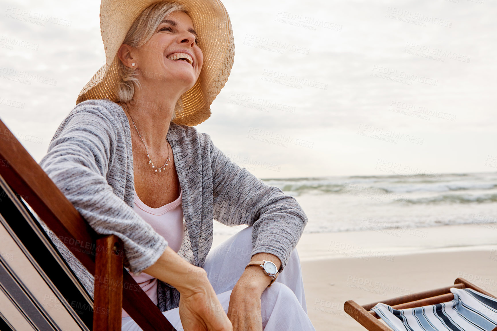 Buy stock photo Cropped shot of an attractive middle aged woman sitting on a lounger at the beach