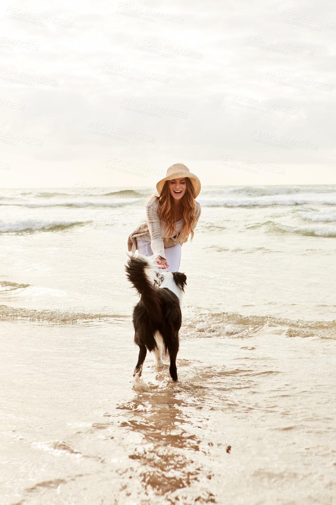 Buy stock photo Shot of a young woman spending some time with her dog at the beach