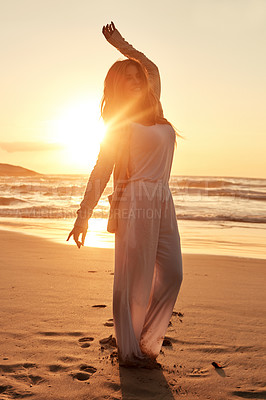 Buy stock photo Shot of a young woman standing with her arms outstretched at the beach