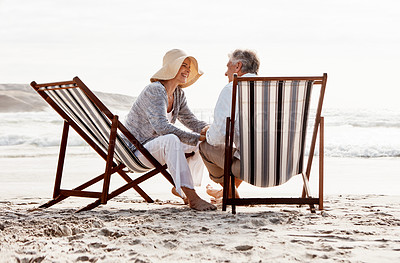 Buy stock photo Full length shot of an affectionate middle aged couple relaxing on loungers at the beach