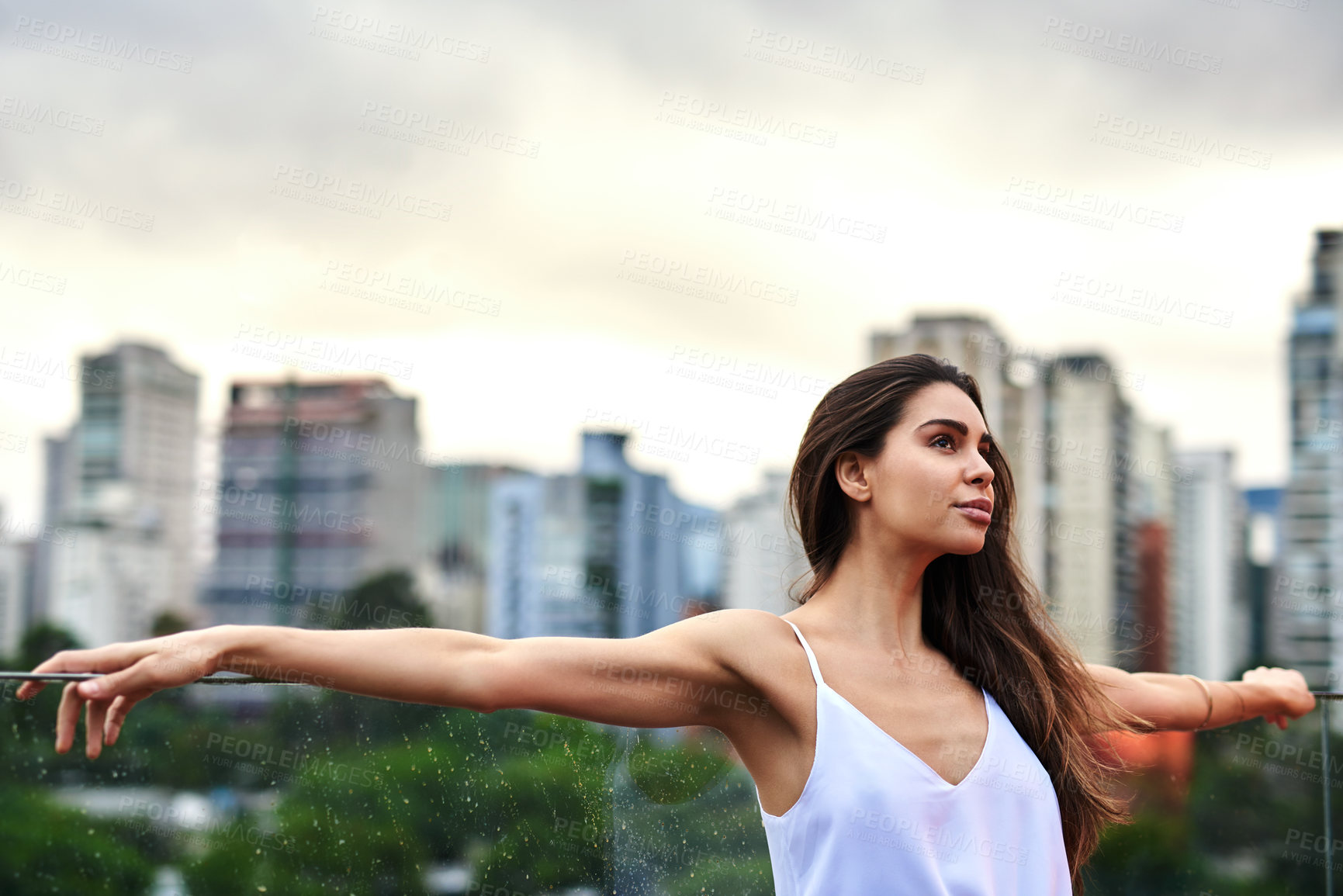 Buy stock photo Cropped shot of an attractive young woman standing on a balcony with her arms outstretched during the day