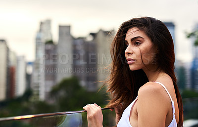 Buy stock photo Cropped shot of an attractive young woman standing on a balcony outdoors during the day