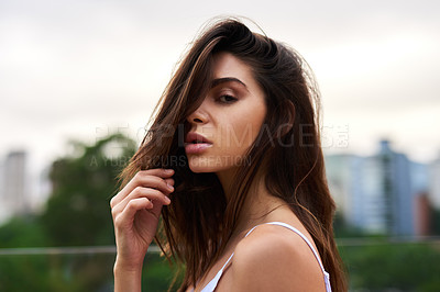 Buy stock photo Cropped portrait of an attractive young woman standing on a balcony outdoors during the day