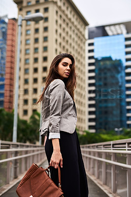 Buy stock photo Cropped portrait of an attractive young woman looking back while walking in the city during the day
