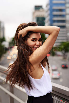 Buy stock photo Cropped portrait of an attractive young woman smiling while standing on a balcony in the city