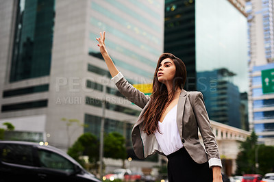 Buy stock photo Cropped shot of an attractive young businesswoman hailing for a cab in the city during the day