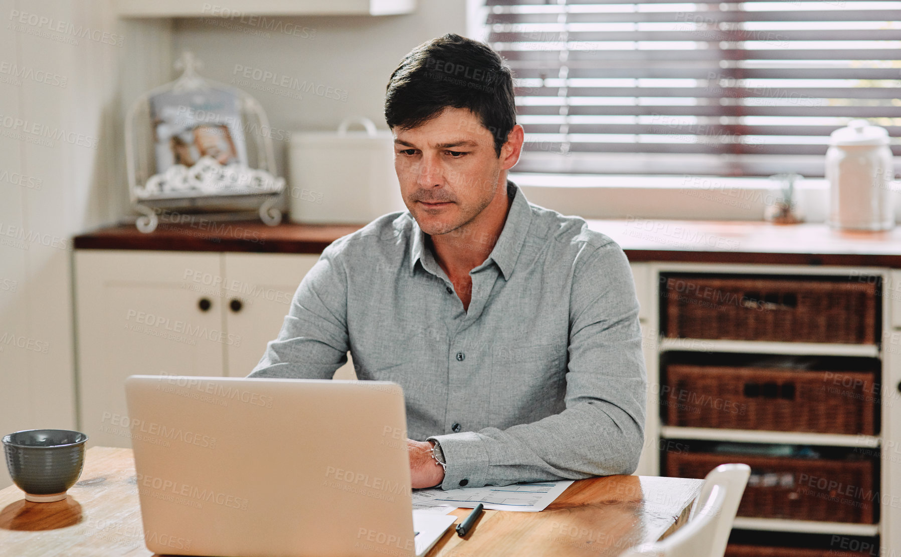 Buy stock photo Cropped shot of a man using his laptop while sitting at home