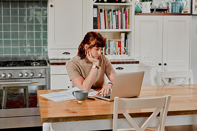 Buy stock photo Shot of a woman sitting at home with paperwork and her laptop