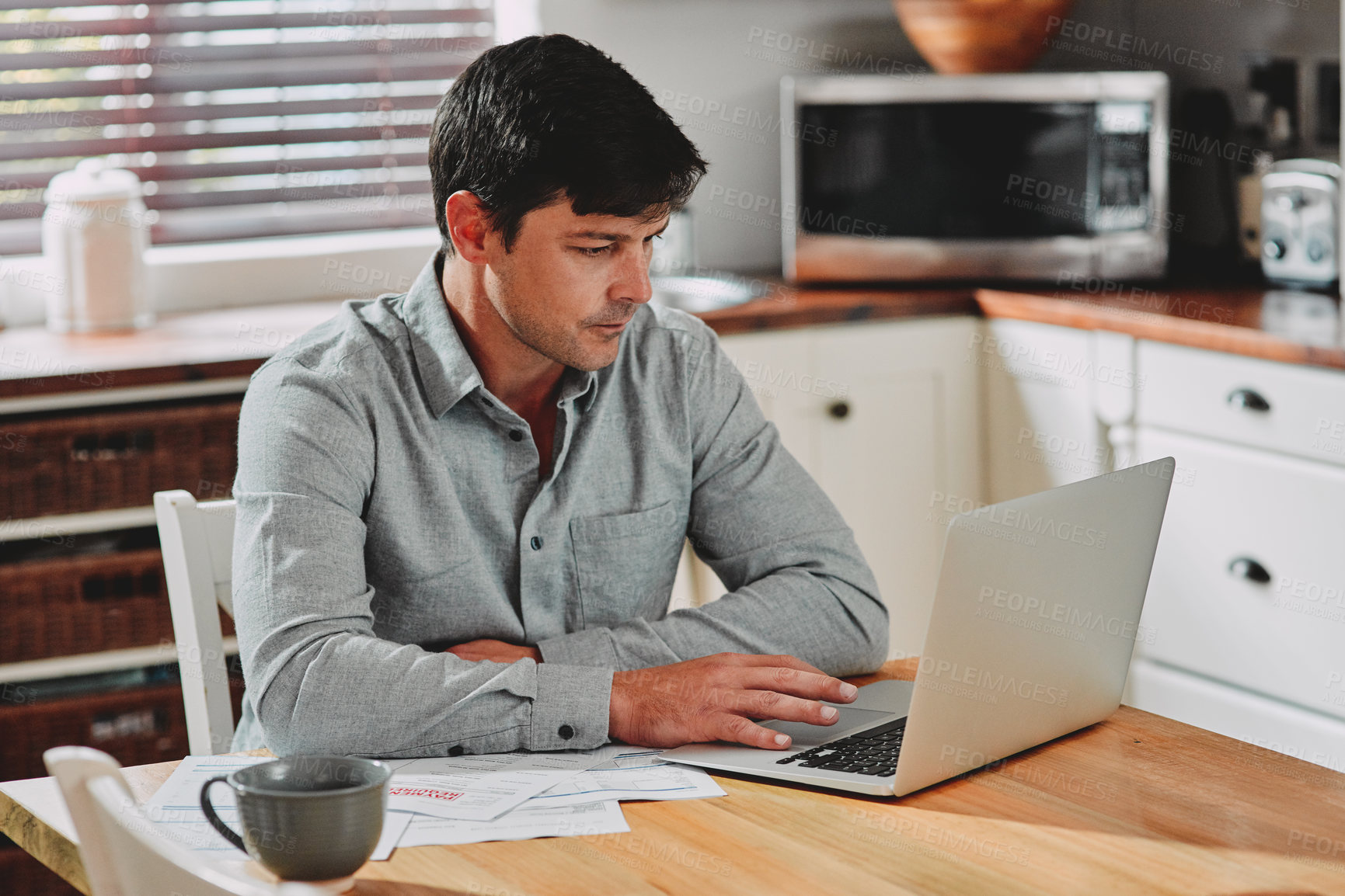 Buy stock photo Cropped shot of a man sitting with paperwork and his laptop at home
