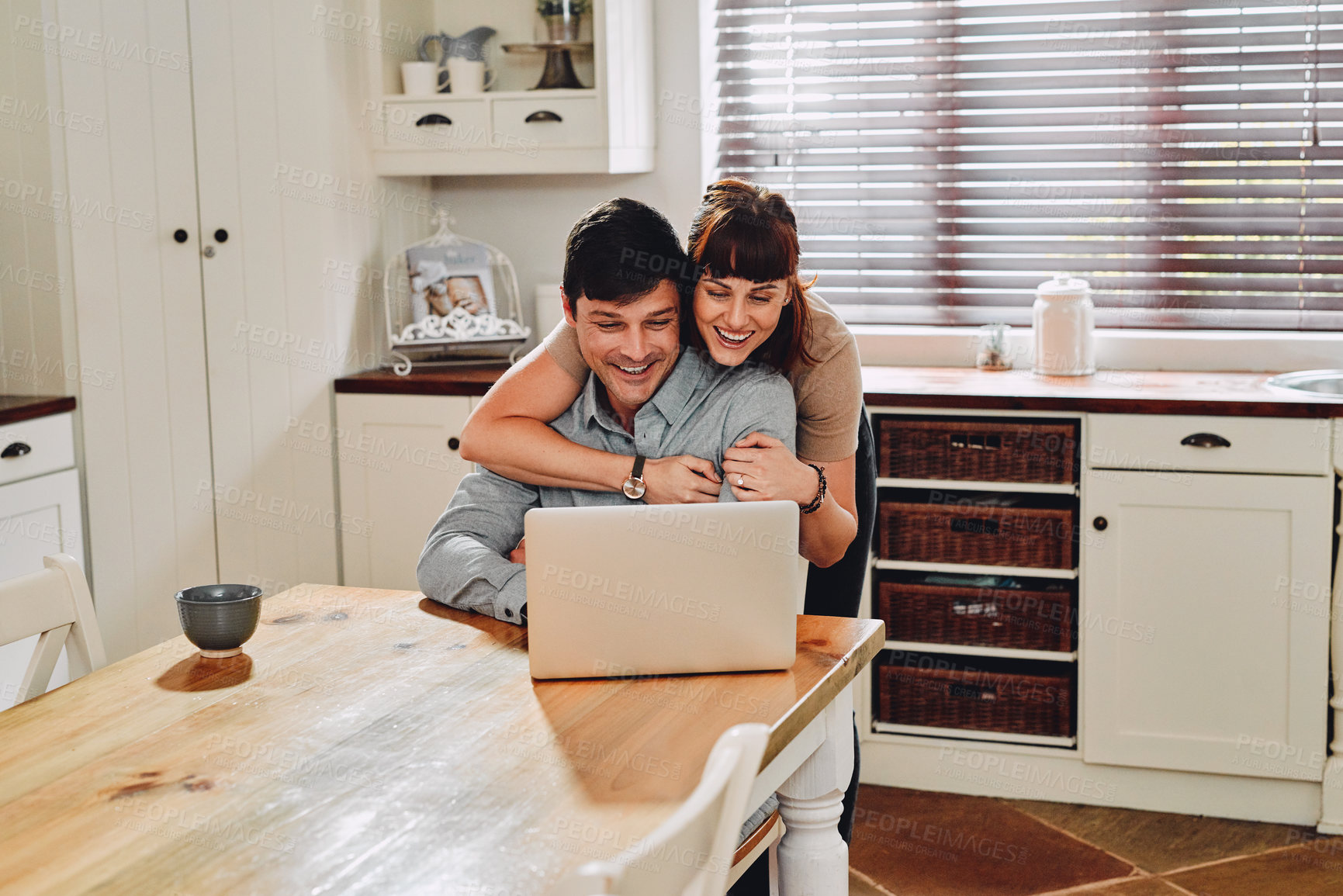 Buy stock photo Shot of a man using his laptop while being embraced by his wife at home