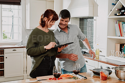 Buy stock photo Shot of a couple using a digital tablet while cooking at home