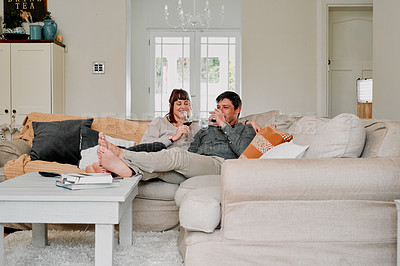 Buy stock photo Shot of a couple having wine while relaxing on the sofa at home