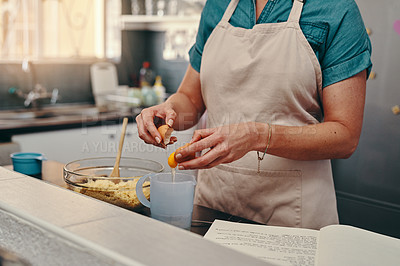 Buy stock photo Cropped shot of an unrecognizable woman cracking egg shells while baking inside her kitchen