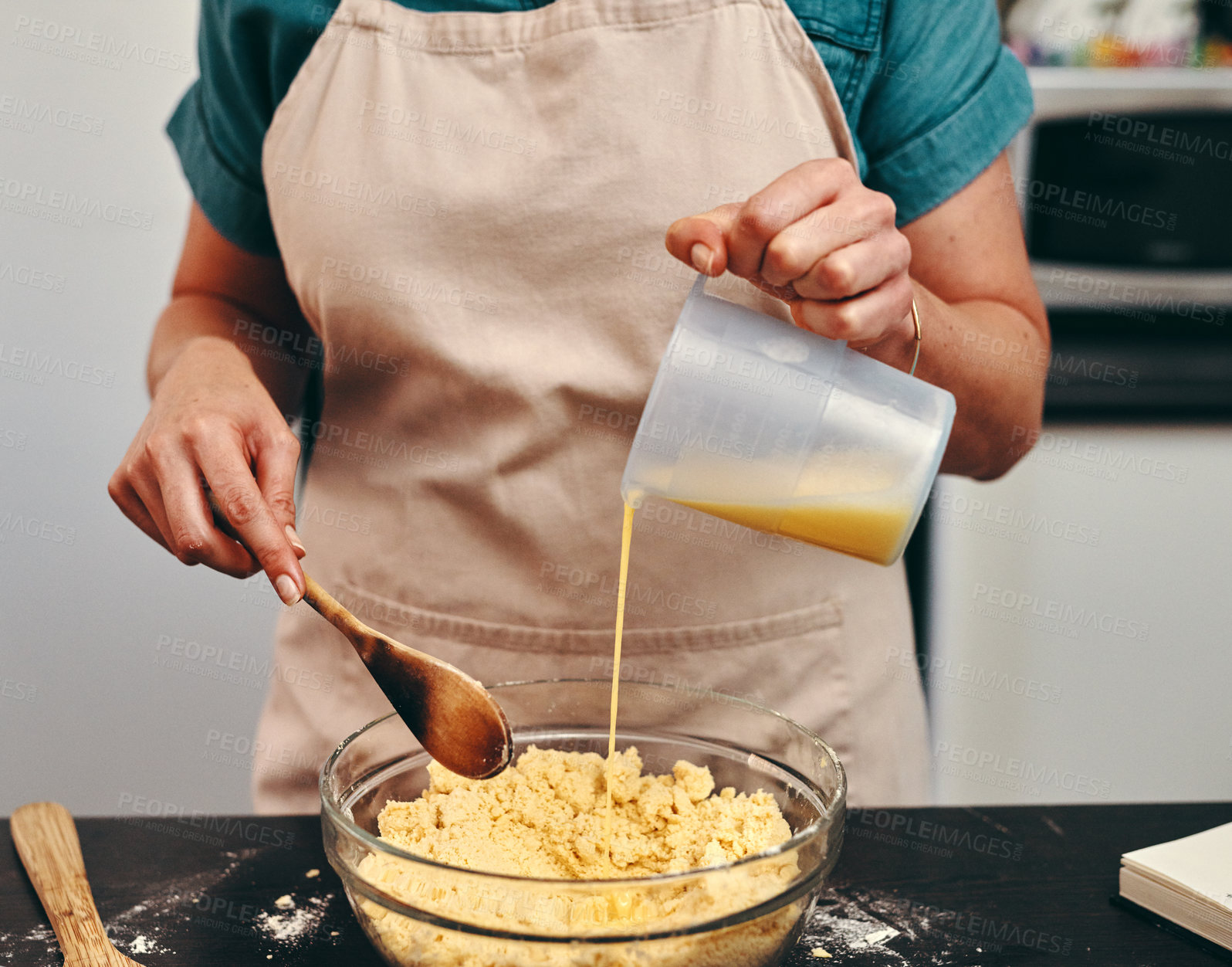 Buy stock photo Baking, bowl and hands of chef in kitchen with wooden spoon, pouring wet mix as ingredients for recipe. Batter, food and glass dish with person at counter of apartment diet, health or nutrition