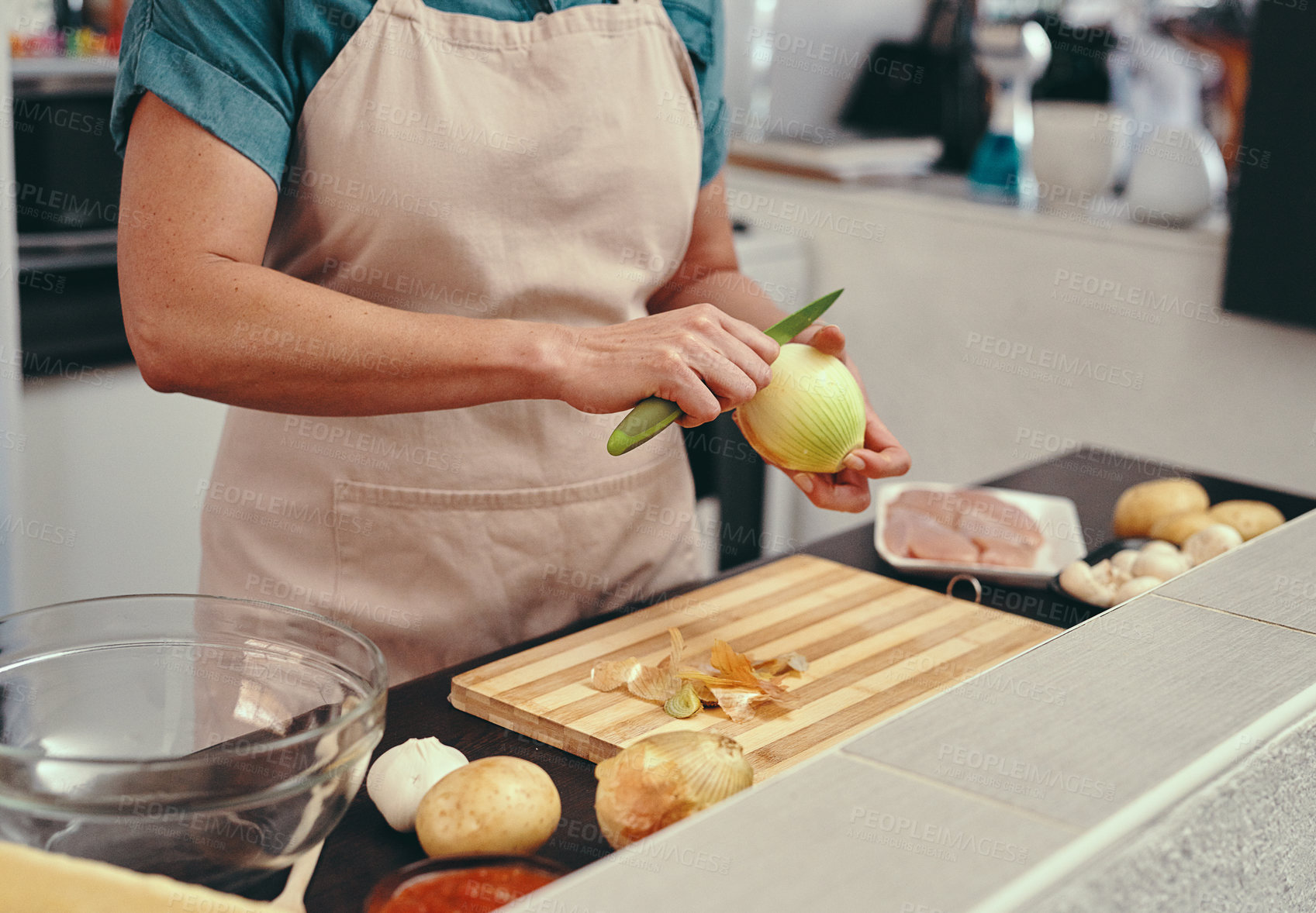 Buy stock photo Cropped shot of an unrecognizable woman slicing an onion while cooking in her kitchen at home
