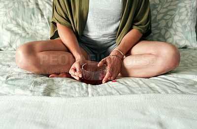 Buy stock photo Cropped shot of an unrecognizable woman sitting on her bed and drinking tea at home