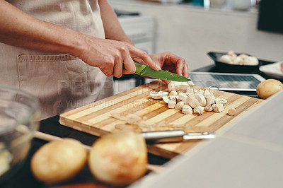 Buy stock photo Cropped shot of an unrecognizable woman chopping up fresh mushrooms while cooking inside her kitchen at home