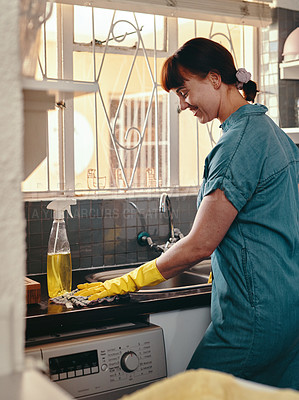 Buy stock photo Shot of an attractive young woman using cleaning detergent to clean her kitchen at home