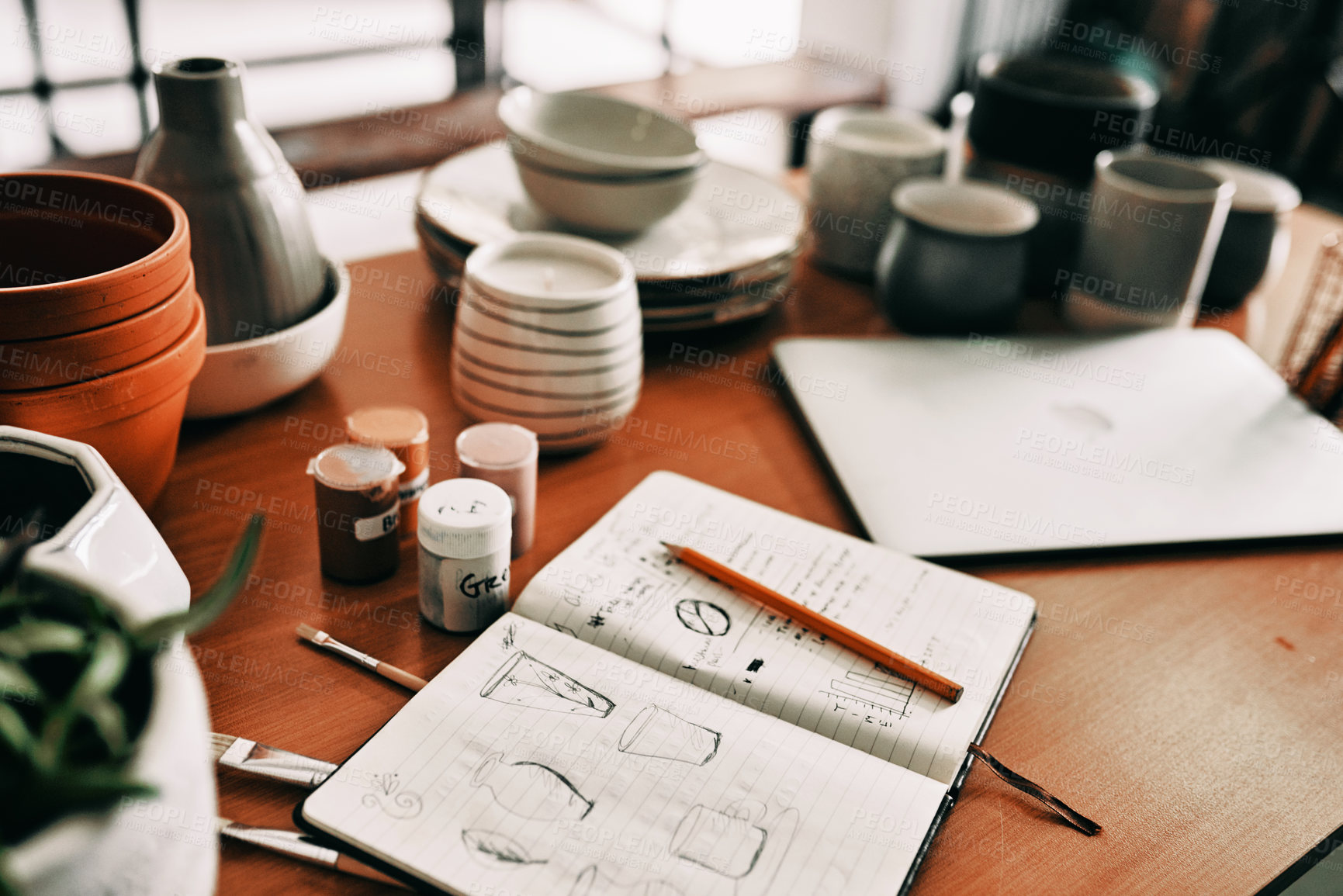 Buy stock photo Cropped shot of a potter's sketches in a notebook on a work desk in her workshop